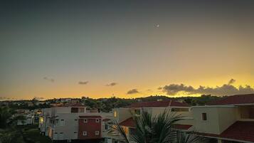 A residential area with houses featuring red-tiled roofs and a clear sky with a crescent moon.