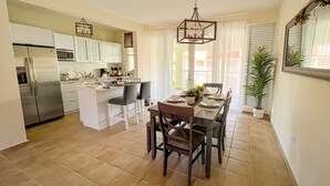 Una cocina moderna con una isla central, electrodomésticos de acero inoxidable y un comedor con mesa y sillas de madera.