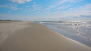 A beach with a wide sandy shore and gentle waves. - Bluff Shoal Motel (Ocracoke)
