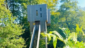 A treehouse with a wooden staircase leading up to it, surrounded by lush greenery and trees.