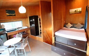 Une chambre à coucher de taille réduite, comprenant un lit, un bureau avec un ordinateur, une chaise et une petite table.