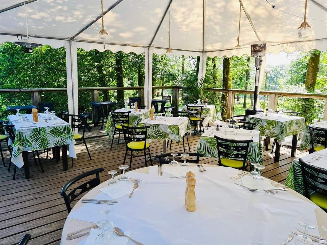 An outdoor dining area with round tables, chairs, and umbrellas.