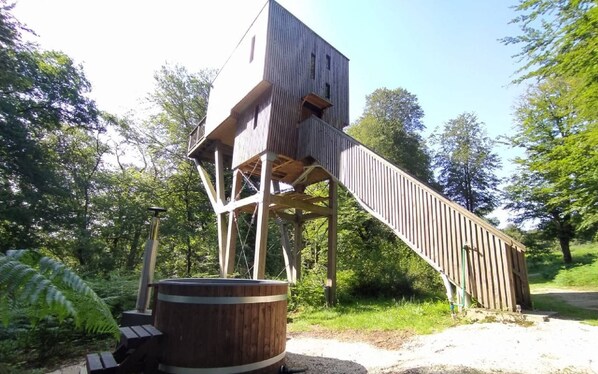 A wooden structure with a staircase leading to a platform, surrounded by greenery. - Treehouse & private SPA (4/5 peoples) (Noues de Sienne)