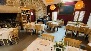 A restaurant with multiple tables set for dining, a stone wall, and a fireplace. - BUNGALOW TERRACE (3pers) with private hot TUB - Forest stopover (NOUES DE SIENNE)