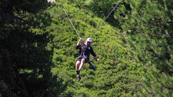 A person ziplining through a forested area.