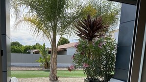 An outdoor patio with a sofa and chairs, a coffee table with two pineapples, and a view of a garden with trees and a building in the background. - A little corner of paradise in Vale de Parra (Guia)