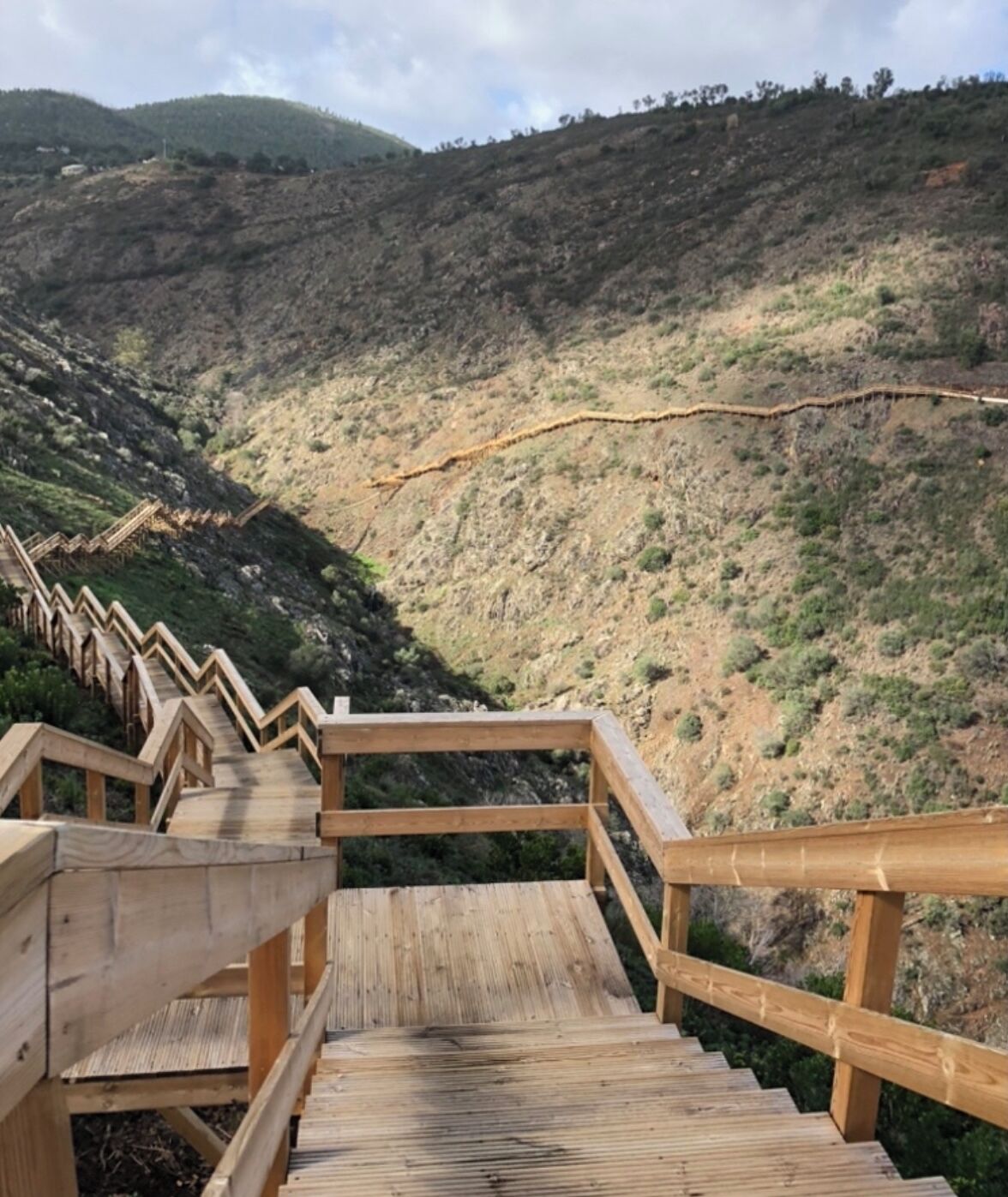Una escalera de madera que sube por una colina, con vistas a un valle.