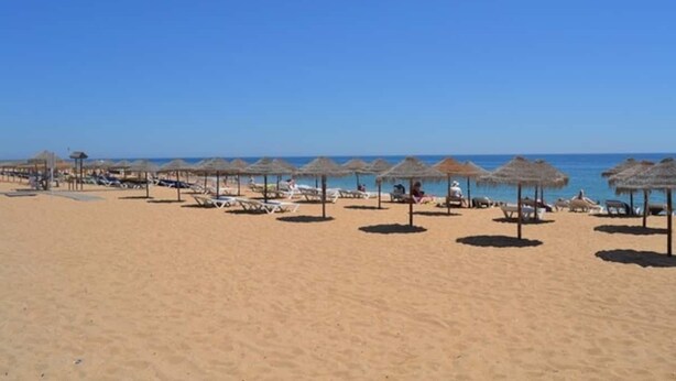 A beach with rows of sun loungers and thatched umbrellas. - Altura T1 Algarve Sun + Beach (Altura)