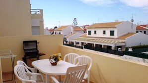 A terrace with a round table and four chairs, a grill, and a small garden. - Altura T1 Algarve Sun + Beach (Altura)