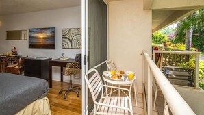 Un balcon avec une table et des chaises pour prendre les repas, un lit, un bureau avec une chaise et des œuvres d’art accrochées au mur.