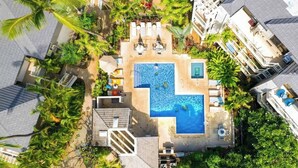 An aerial view of a resort with a central swimming pool, lounge areas, and lush greenery. - Wailea Luxury Retreat | Walk to Beach & Shops (Wailea-Makena)