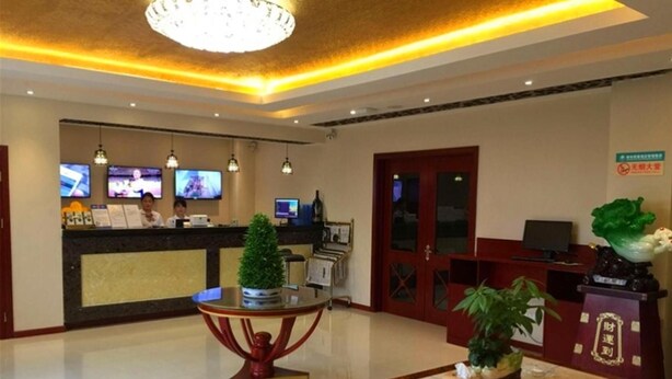A hotel lobby with a reception desk, multiple televisions, a chandelier, and a reception counter with a decorative plant. - Greentree Inn Qinhuangdao Changli County Railway S (Qinhuangdao)