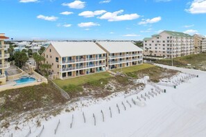 Een hotel aan het strand met meerdere balkons, een zwembad en een zandstrand.
