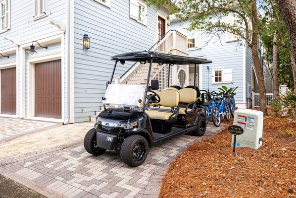 Un carrito de golf estacionado frente a una casa con garaje, una escalera y un letrero que indica zona privada.