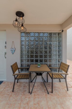 A dining area with a table and chairs, a decorative light fixture, and a wall with a mosaic pattern.