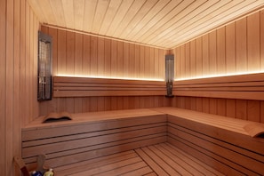 Uma sauna com paredes e bancos de madeira, equipada com grelhas de ventilação e um banco com um livro.