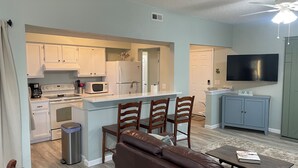 A compact living space with a kitchenette, a dining area, a sofa, and a TV. - Newly remodeled. Steps away from the ocean! Condo in Kill Devil Hills. (Kill Devil Hills)