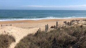 A sandy beach with a wooden fence and dunes. - Newly remodeled. Steps away from the ocean! Condo in Kill Devil Hills. (Kill Devil Hills)