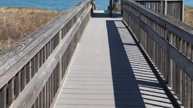 A wooden boardwalk leading to a gazebo with a view of the ocean. - Newly remodeled. Steps away from the ocean! Condo in Kill Devil Hills. (Kill Devil Hills)