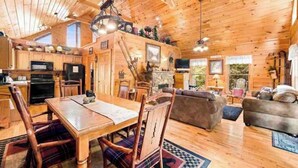 Interior d'una cabana de fusta amb menjador, cuina i sala d'estar.