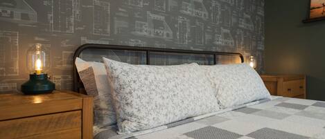 Un dormitorio con una cama, una mesita de noche y una pared con dibujos arquitectónicos.