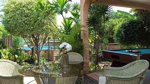 An outdoor pool area with a glass table, wicker chairs, and a pool table. - Villa Sea View (Saint-Leu)