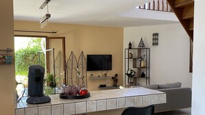 A modern kitchen with a built-in TV, a coffee machine, and two bar stools. - Villa Sea View (Saint-Leu)