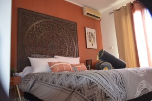 A bedroom with a large bed, a decorative headboard, an air conditioning unit, and a framed picture on the wall. - Villa Sea View (Saint-Leu)