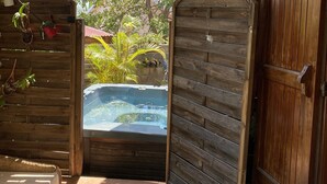 A wooden gate leading to a hot tub area with a tiled floor and a wicker sofa. - Villa Sea View (Saint-Leu)