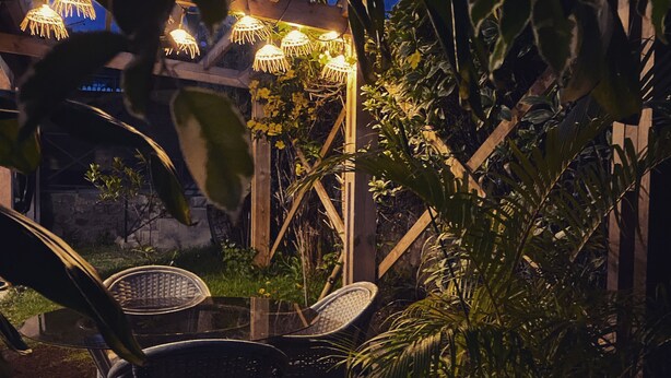An outdoor patio area with wooden flooring, two wicker chairs, and a potted plant. - Villa Sea View (Saint-Leu)