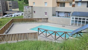A swimming pool with a wooden deck and a stone pillar labeled "Skiset Location". - Apartment La Foux Heated pool access (La Foux d'Allos)