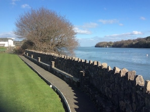 A stone wall beside a body of water, a grassy area, and a tree. - Lovely Victorian House close to the sea in North Wales (Bangor)