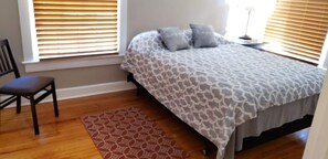 Cozy retreat with a comfortable bed, chair, and natural light.