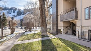Un edificio moderno con un espacio exterior cubierto, una escalera y vistas a una montaña nevada.