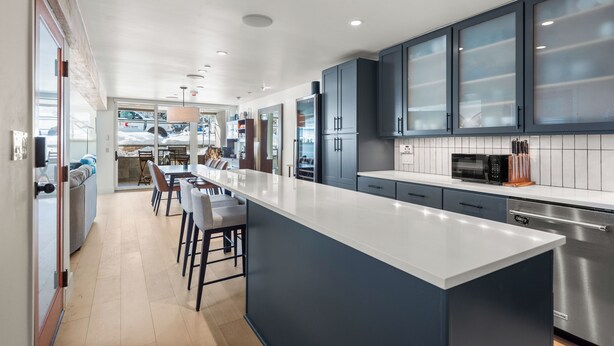 Una cocina moderna con una isla grande, armarios oscuros y electrodomésticos de acero inoxidable.