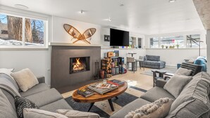 Una sala de estar moderna con chimenea, sofá, mesa de centro y televisor de pantalla plana.