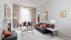 Un salon comprenant un canapé, une table basse, une cheminée et un coin repas avec des chaises et une table.
