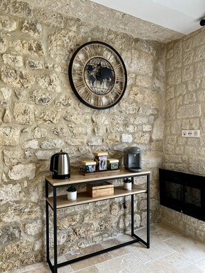 A stone wall with a round clock, a coffee maker, and a kettle on a wooden console table. - Private Jacuzzi and Sauna Suite at Villa Del Castagnol (Saint-Nexans)