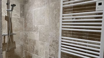 A shower with a handheld showerhead and a wall-mounted control panel.