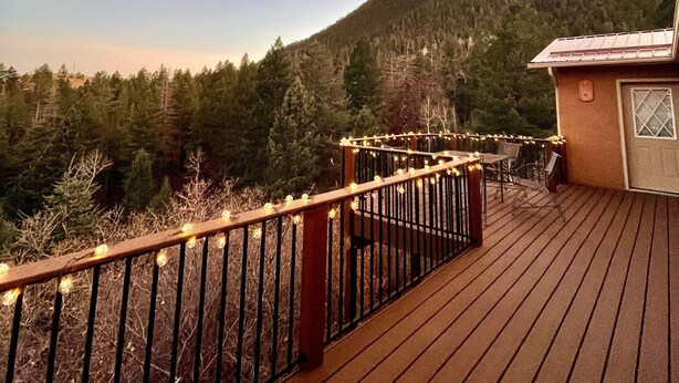 A wooden deck with a railing, overlooking a forested hillside.