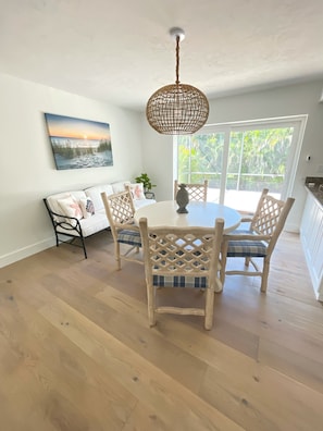 A dining area with a round table, four chairs, and a hanging light fixture.