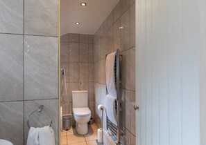 Een moderne badkamer met een douchecabine van glas, een toilet en een handdoekhouder.