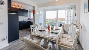 A modern kitchen with dark cabinets and a dining area with a floral tablecloth. - Sea View 3 Bedroom Seaside Property (Chichester)