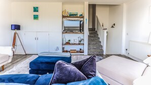 A modern living room with a sofa, a coffee table, and a staircase leading to an upper floor. - Sea View 3 Bedroom Seaside Property (Chichester)