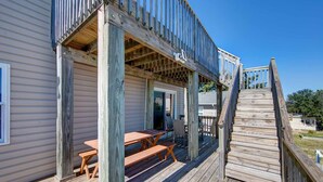 A wooden deck with a picnic table and chairs, a covered area with a door, and a wooden staircase leading up to a deck. - Ocean View- 5 min Walk to Beach, Volleyball (Kill Devil Hills)
