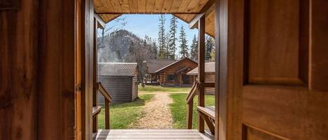 A wooden cabin with a wooden deck leading to a covered porch.