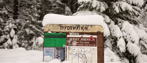 Un panneau d’information recouvert de neige, avec une carte et un panneau vert.