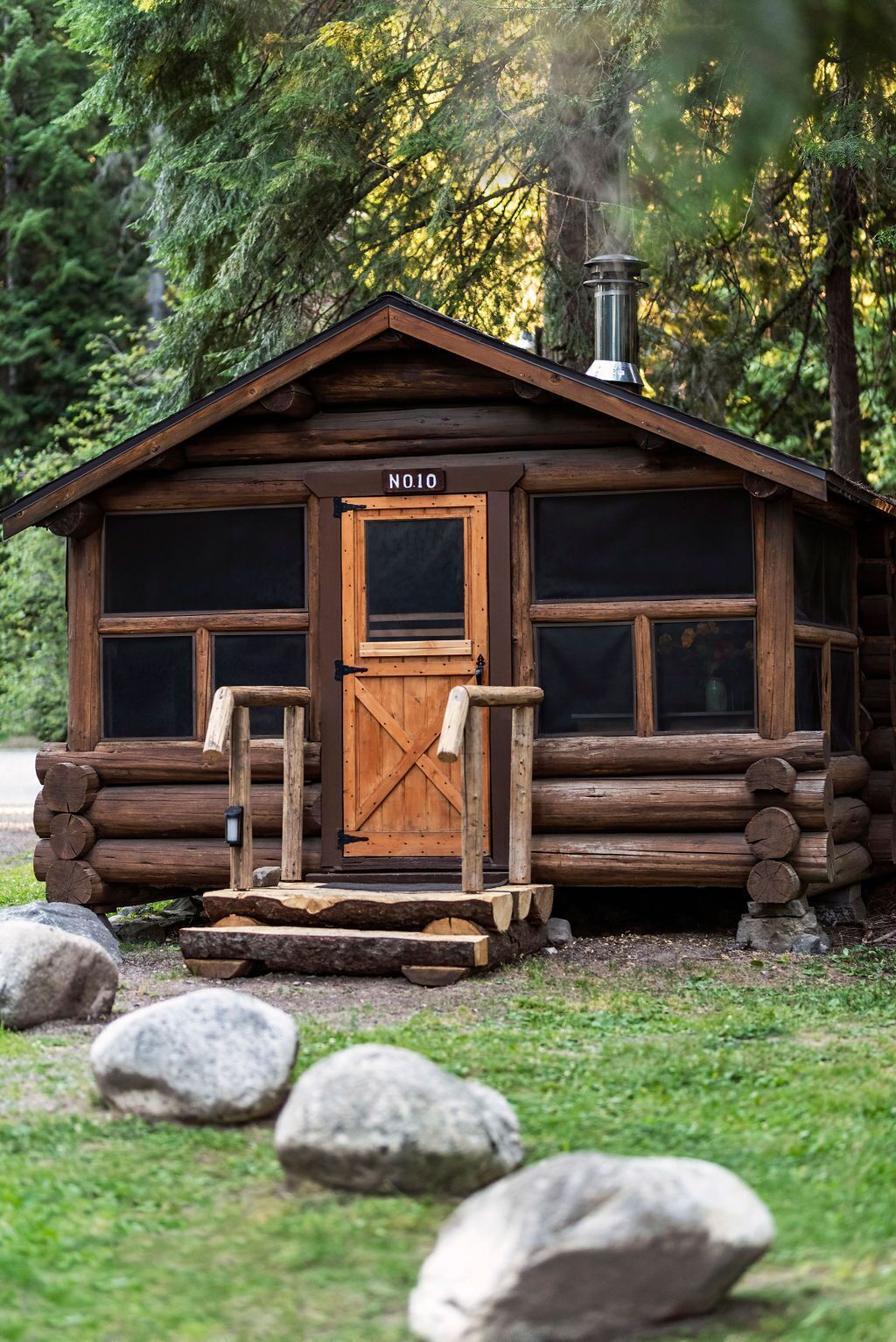 A rustic cabin with a wooden door labeled "NO10," a chimney, and a porch with a bench.