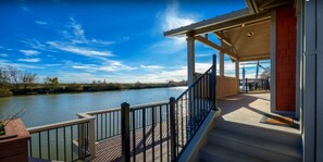A waterfront property with a deck, railing, and steps leading to a covered area. - Waterfront retreat, year round fishing, boating, wine tasting. 1 hr from SF! (Isleton)