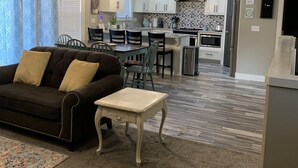 A modern living room with a sofa, a coffee table, and a dining area with chairs.